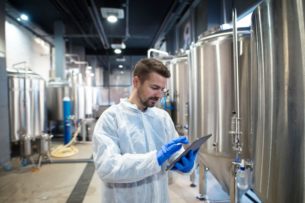 Technologist using tablet in food factory production line. Factory worker controlling production.-1