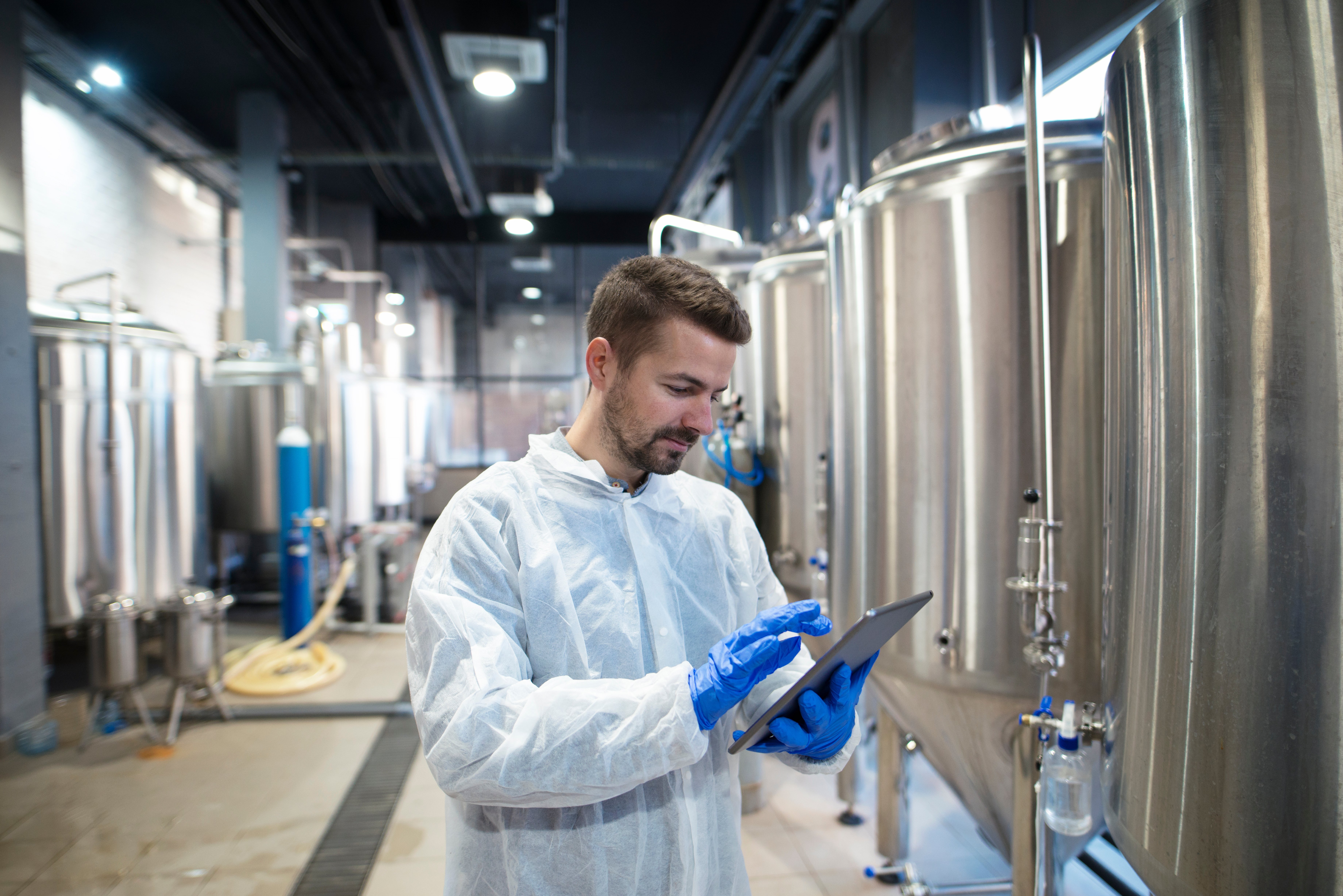 Technologist using tablet in food factory production line. Factory worker controlling production.